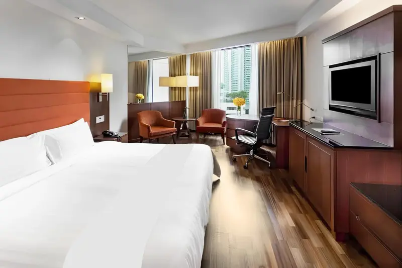 Chambre d'hôtel lumineuse avec un lit blanc et un espace bureau.