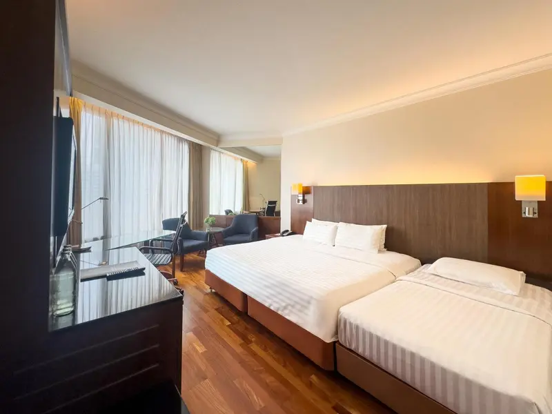 Chambre lumineuse avec lits jumeaux et bureau.