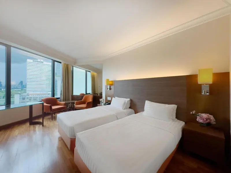 Une chambre d'hôtel lumineuse avec deux lits simples et une vue sur la ville.