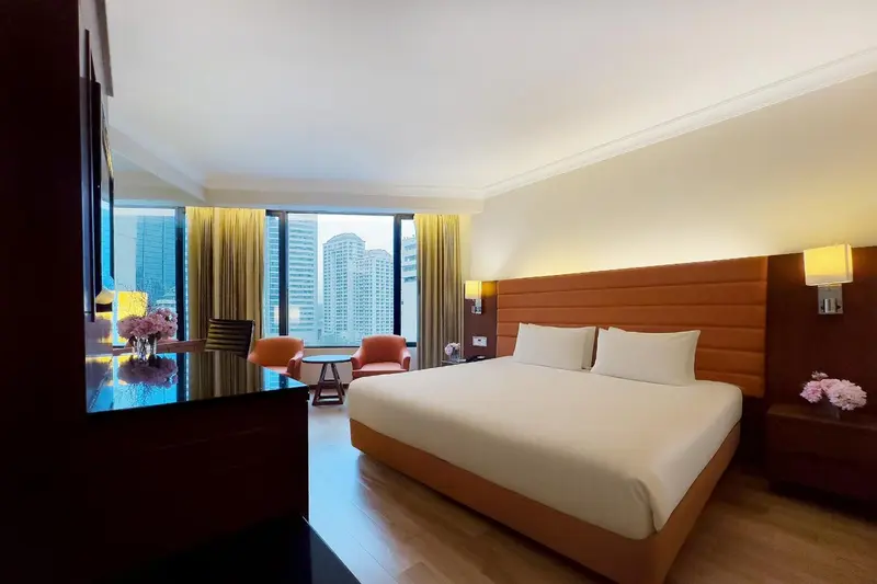Une chambre lumineuse avec un grand lit et un bureau près d'une fenêtre.