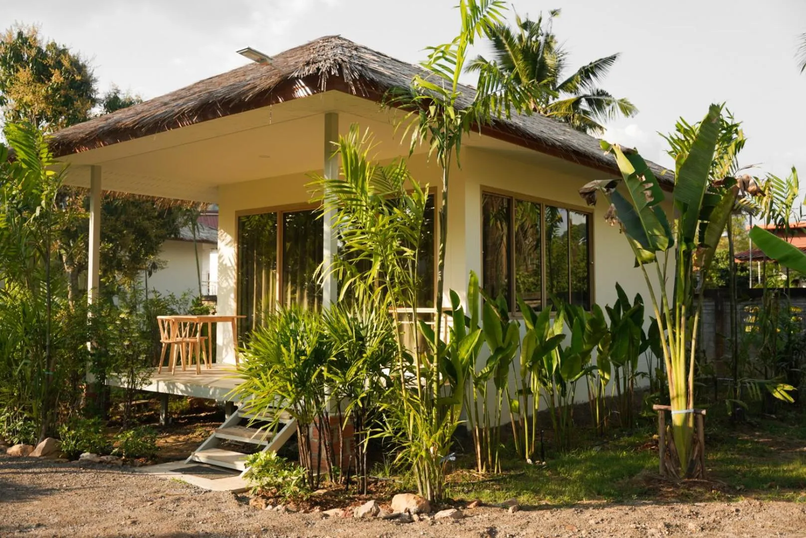 Petite maison de style tropical avec une terrasse en bois et une végétation luxuriante.