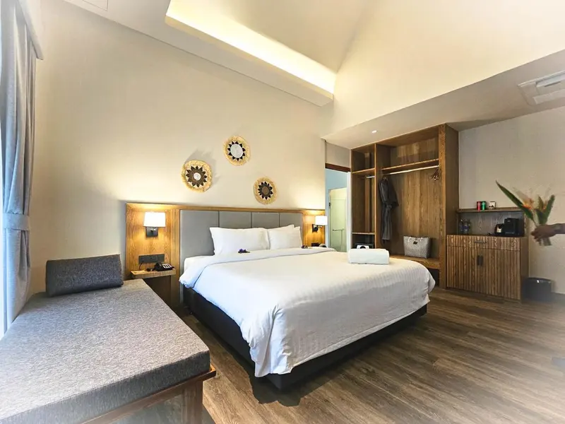 Une chambre lumineuse avec un grand lit et un coin salon.