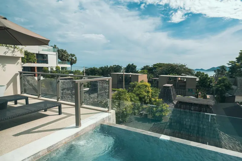 Terrasse avec piscine à débordement donnant sur un paysage verdoyant et la mer.