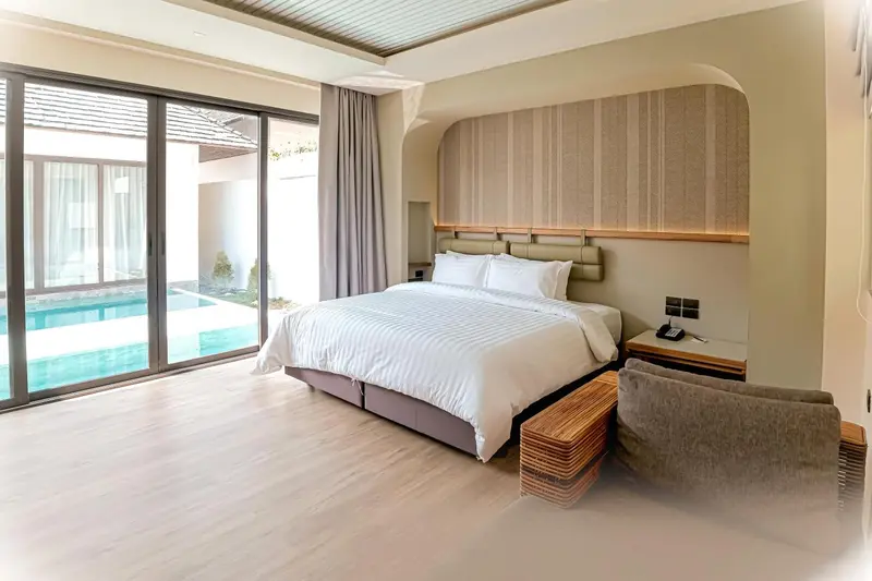 Une chambre lumineuse avec un grand lit et un accès à une piscine.