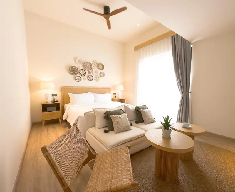Une chambre lumineuse avec un lit double et un coin salon.