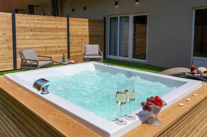 Un jacuzzi extérieur avec des coupes de champagne et des fraises.