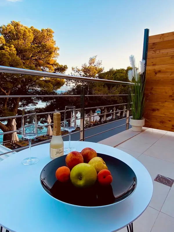 Une table ronde avec des fruits et une bouteille de champagne sur une terrasse.