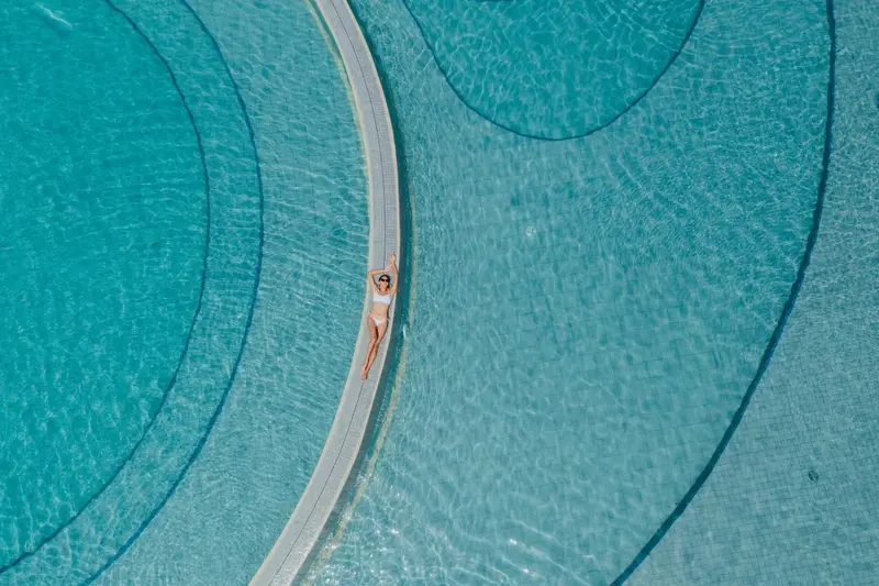 Une personne se relaxe au bord d'une piscine aux formes géométriques.