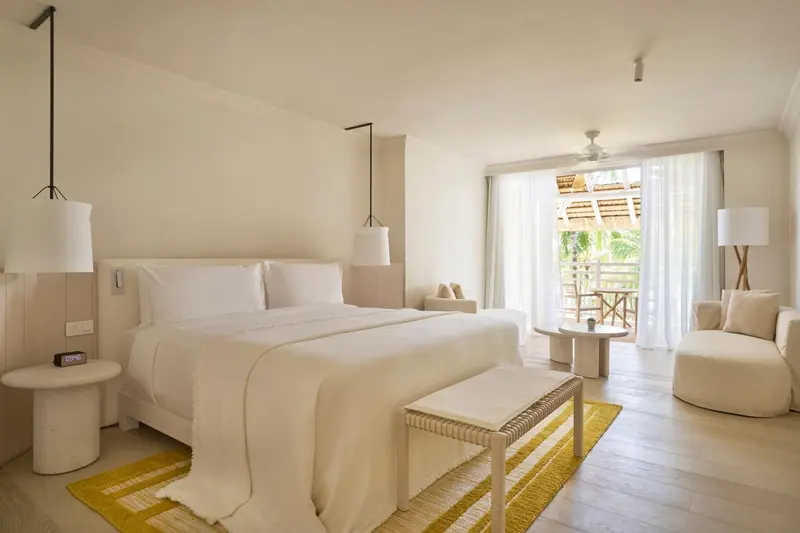 Chambre lumineuse avec un grand lit et un accès à une terrasse.
