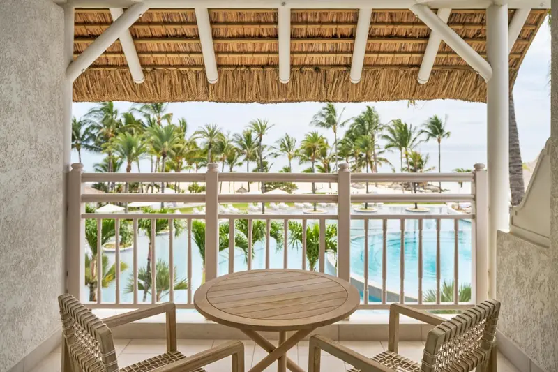 Une terrasse ombragée donne sur une piscine et la mer.