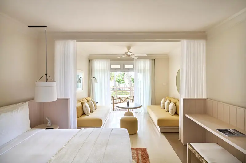 Une chambre lumineuse s'ouvre sur une terrasse avec salon et vue sur la végétation.