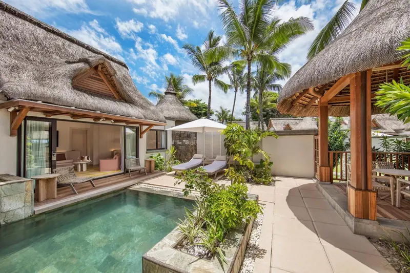 Petite piscine privee devant des bungalows aux toits de chaume.