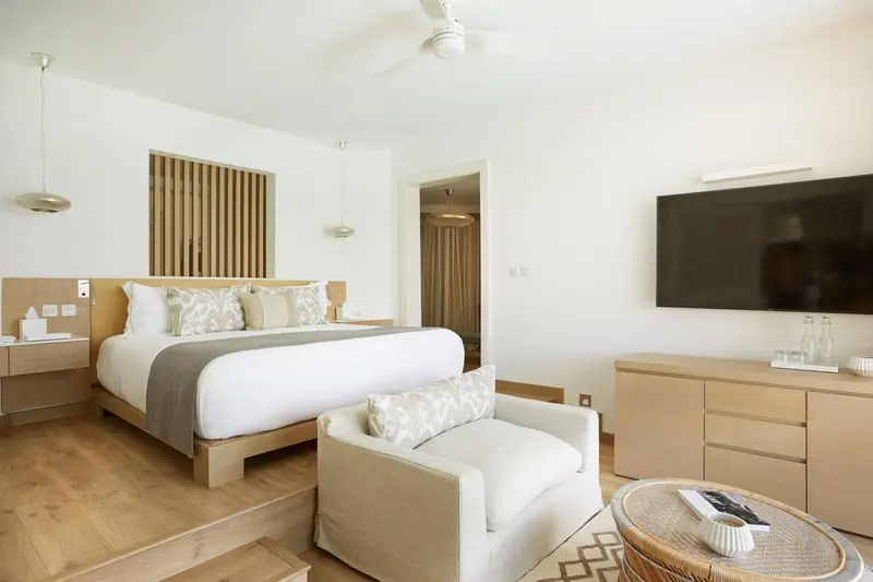 Une chambre lumineuse avec un grand lit et un fauteuil.