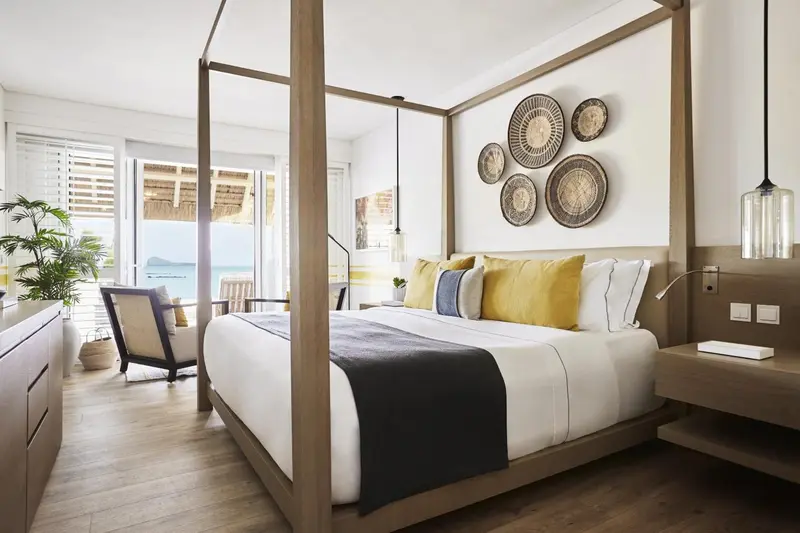 Une chambre lumineuse avec un grand lit à baldaquin et une décoration murale en fibres naturelles.