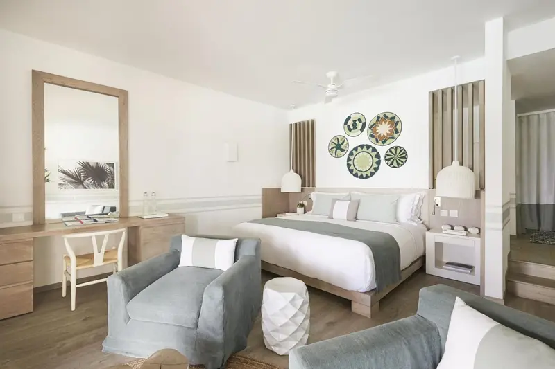 Une chambre lumineuse avec un grand lit et des fauteuils confortables.