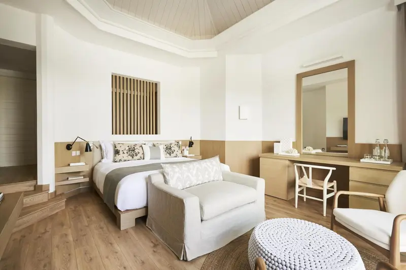 Une chambre lumineuse avec un lit double et un coin salon.