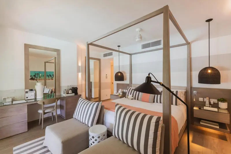 Une chambre lumineuse avec un grand lit à baldaquin et un coin salon.