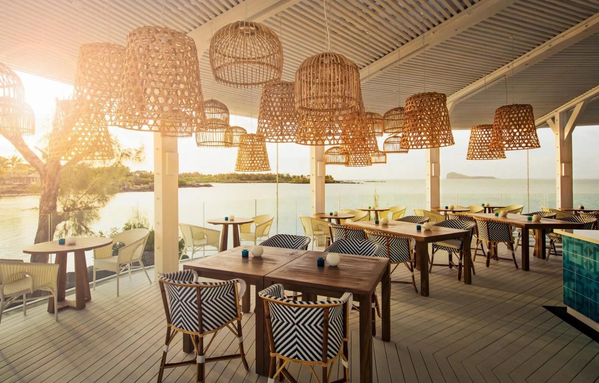 Une terrasse ombragée avec des tables et des chaises en bois face à la mer.