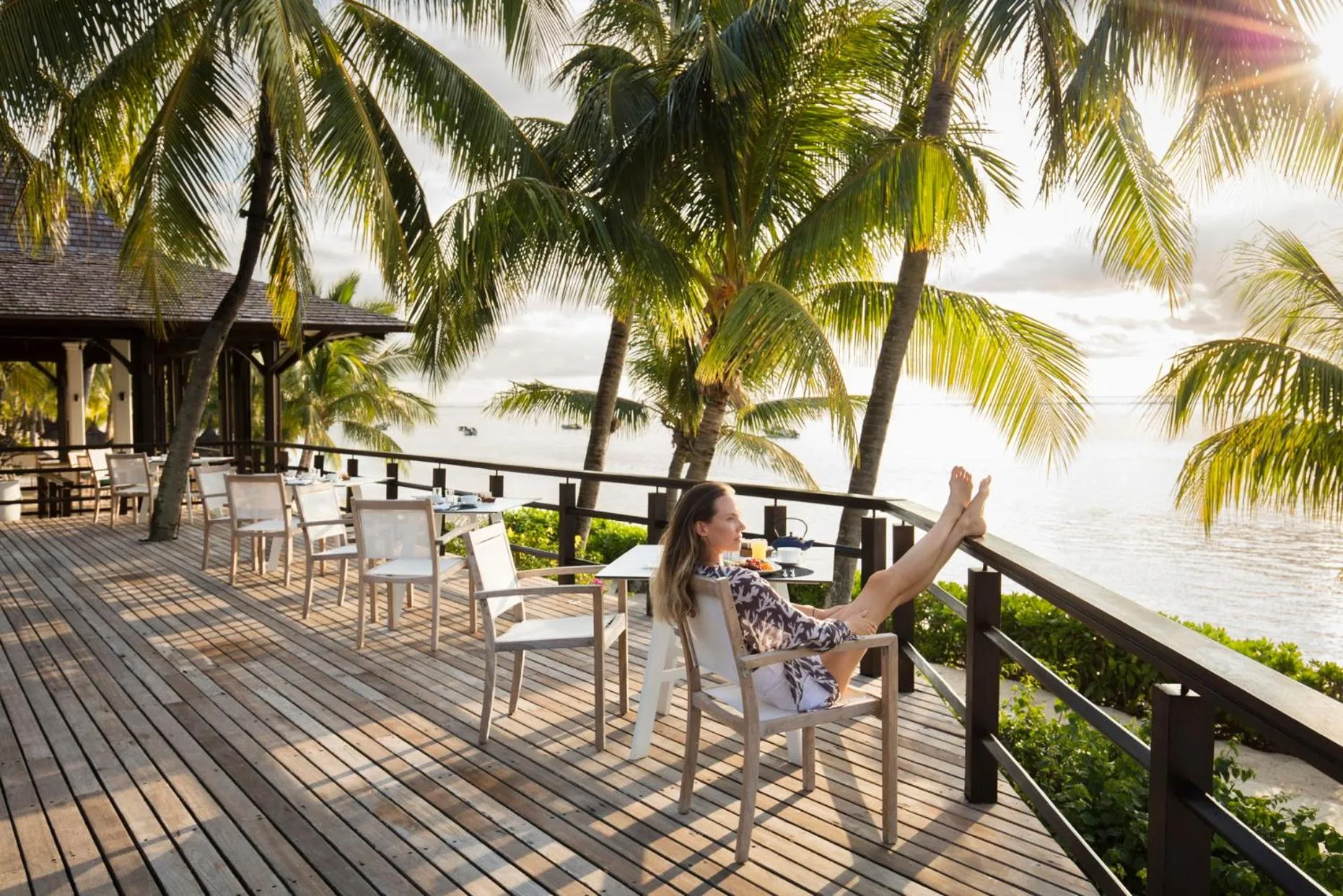 Une femme se détend sur une terrasse en bois face à la mer.
