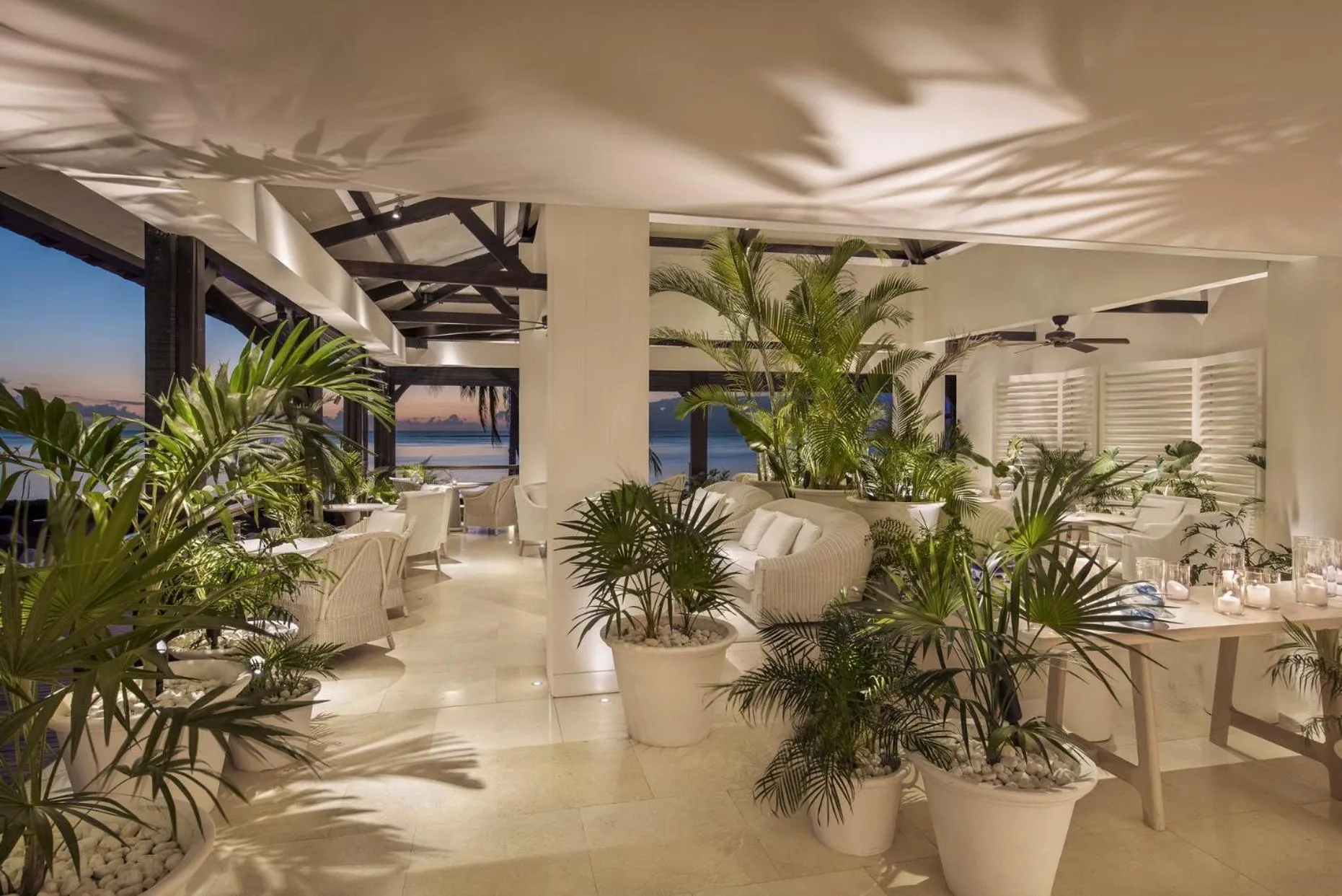 Une salle lumineuse et ouverte avec des tables dressées et une vue sur la mer.