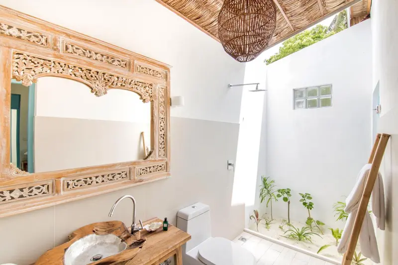 Une salle de bain lumineuse avec une douche à l'italienne et un miroir sculpté.