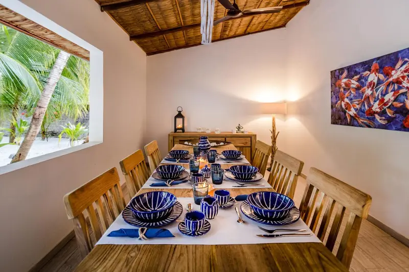 Une table de repas est dressée dans une salle à manger lumineuse.