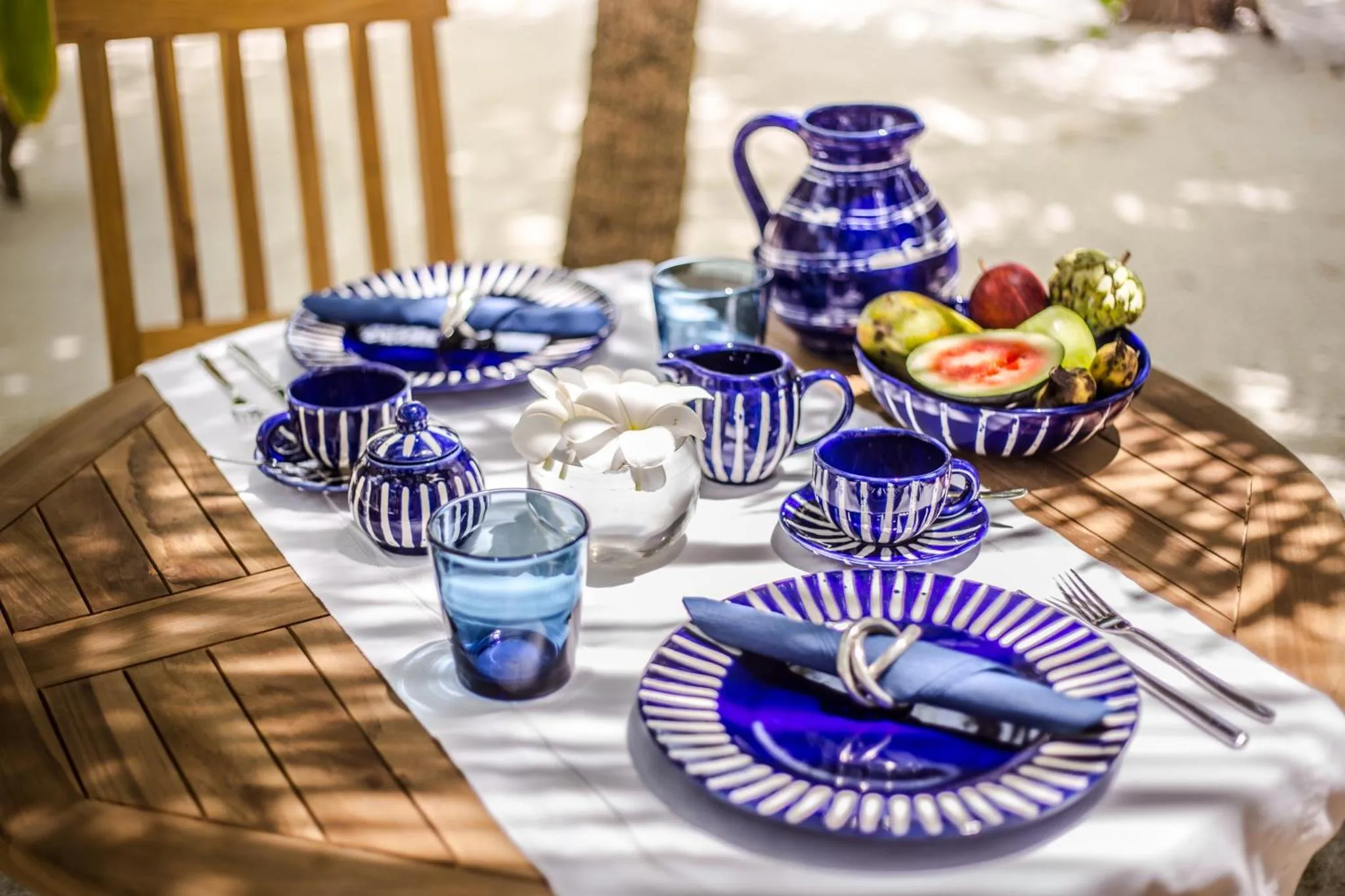 Une table en bois dressée avec de la vaisselle bleue et des fruits frais.