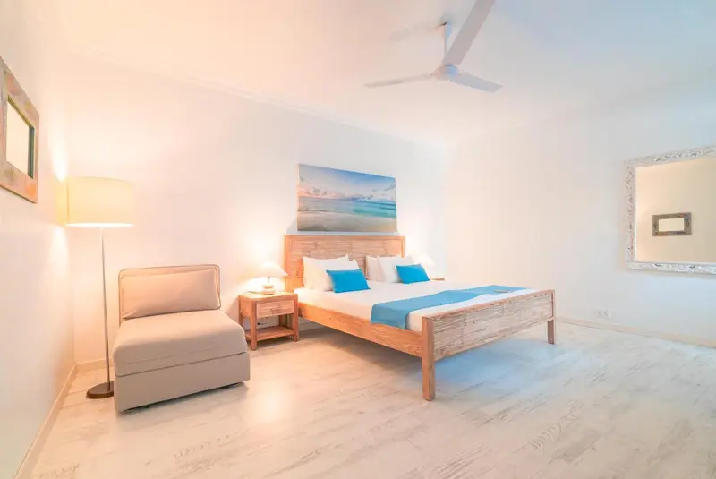 Une chambre lumineuse avec un lit et un fauteuil.
