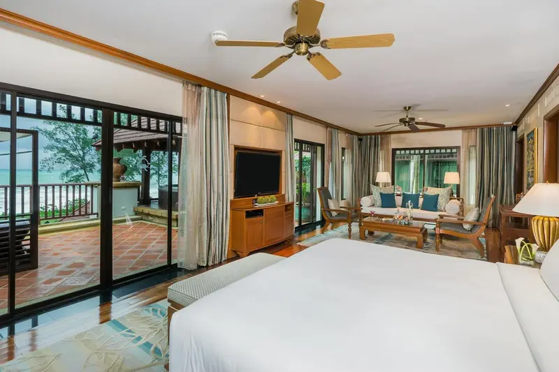 Une chambre spacieuse avec un grand lit et un coin salon donnant sur une vue sur la mer.