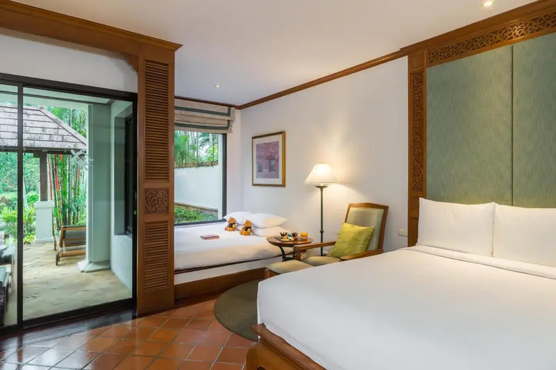 Une chambre lumineuse avec un lit double et un coin salon.