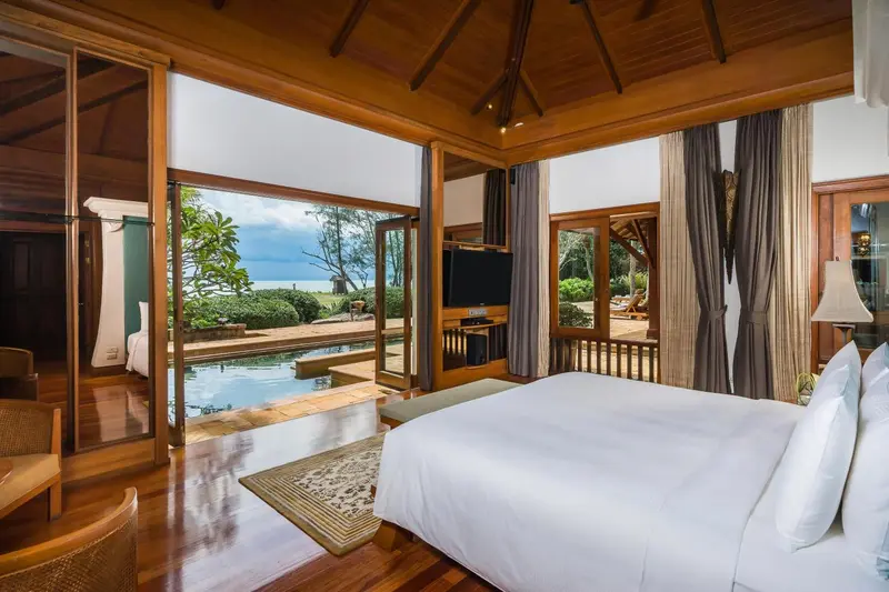Chambre lumineuse avec lit king-size donnant sur une piscine et la mer.
