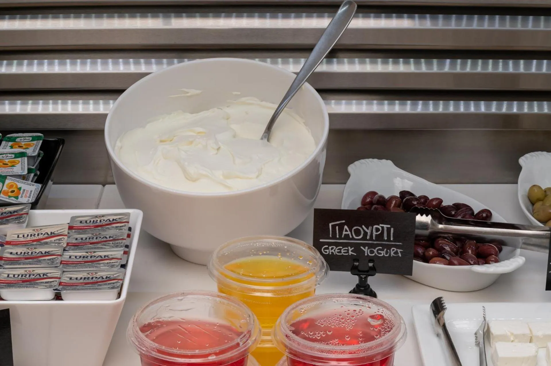 Un buffet propose des yaourts grecs, des fruits et des confitures.