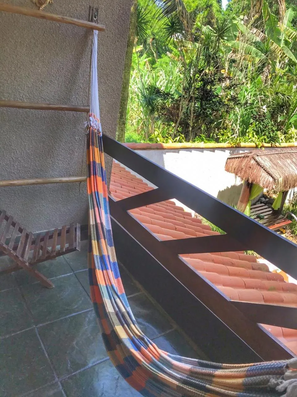 Un hamac coloré est suspendu sur une terrasse carrelée.
