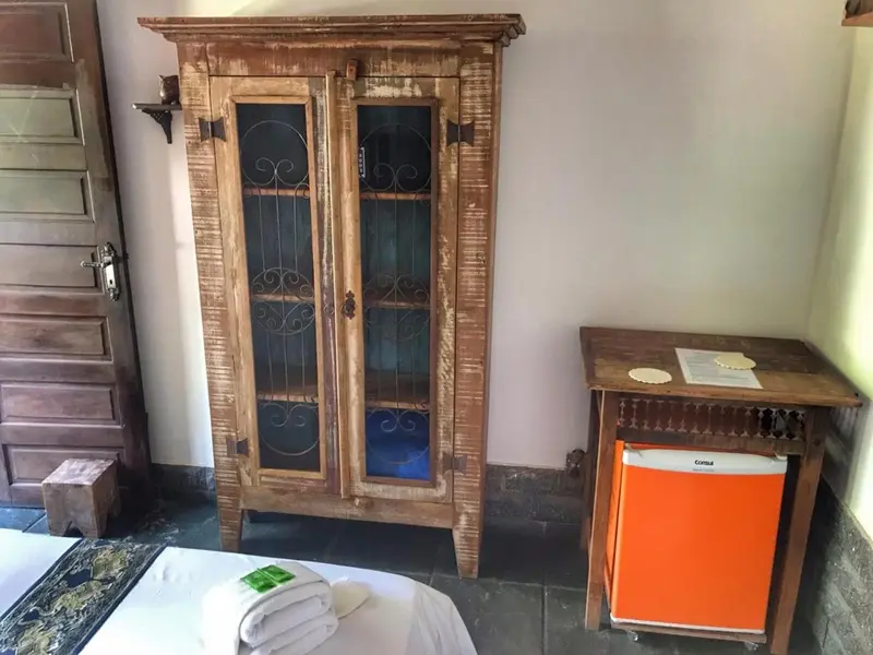 Une armoire en bois et un petit réfrigérateur orange dans une chambre.