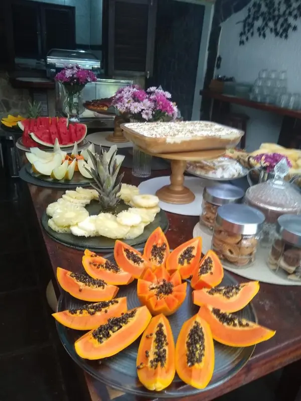 Une table garnie de fruits frais et de pâtisseries est présentée en buffet.