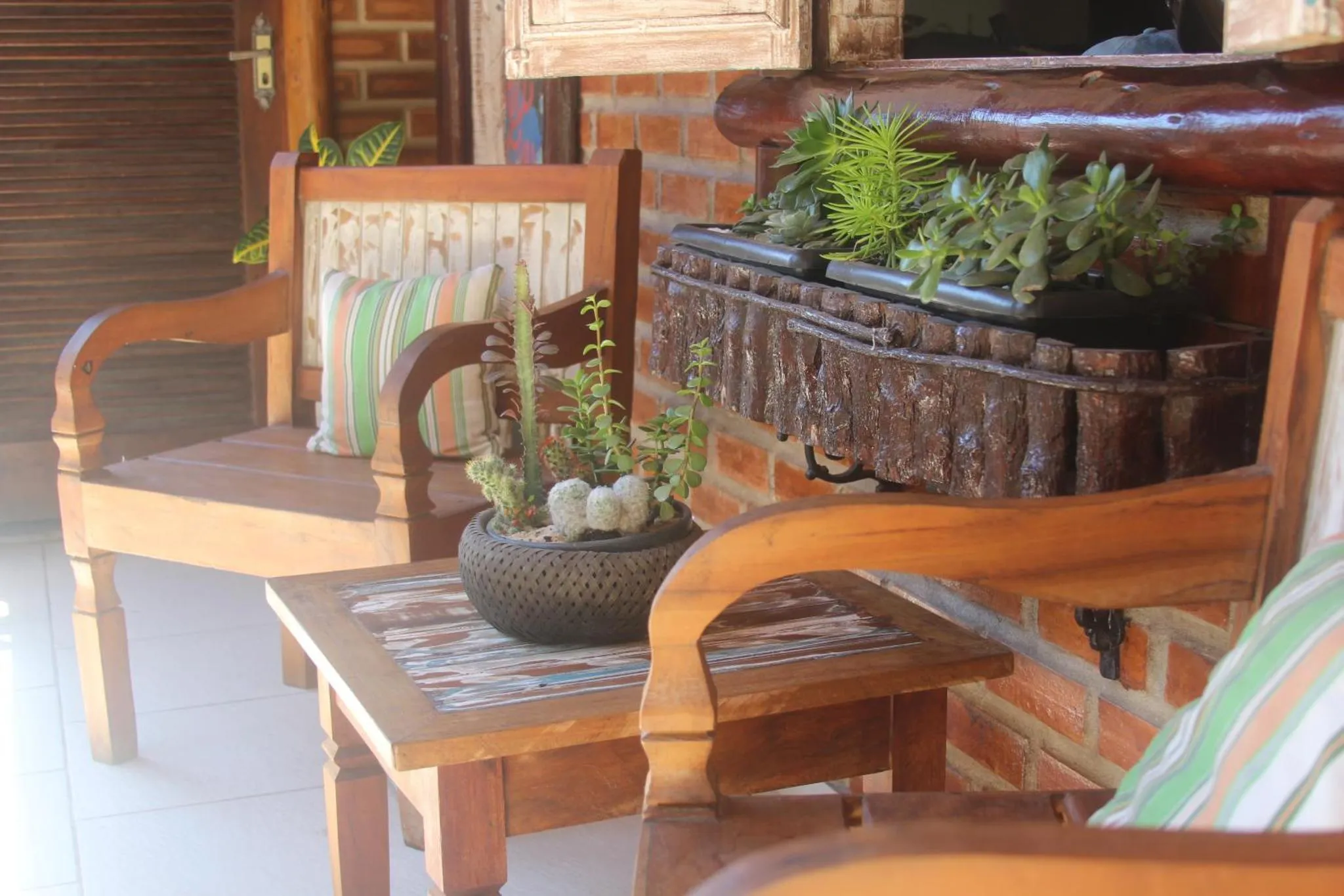 Deux fauteuils en bois ornés de coussins se trouvent sur une terrasse.