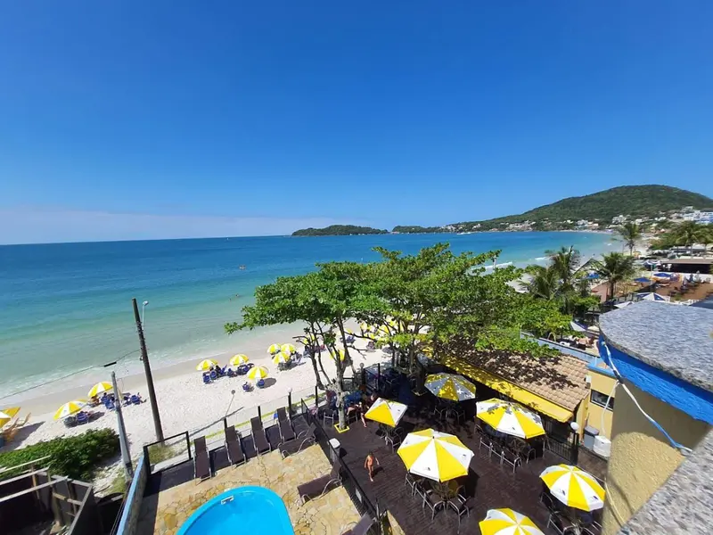 Terrasse ombragée donnant sur une plage de sable fin et une mer turquoise.