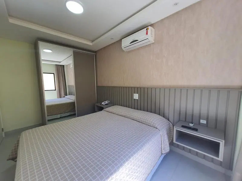 Une chambre avec un grand lit et un climatiseur mural.