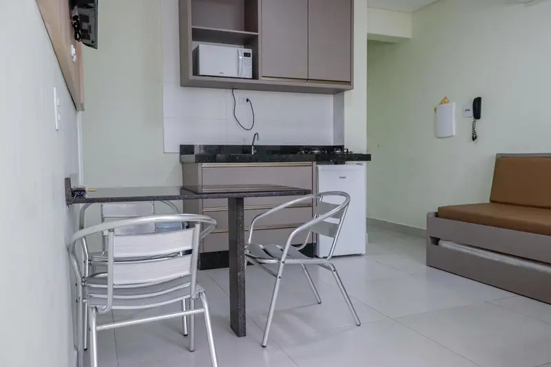 Une kitchenette avec une table et des chaises est visible dans une pièce lumineuse.