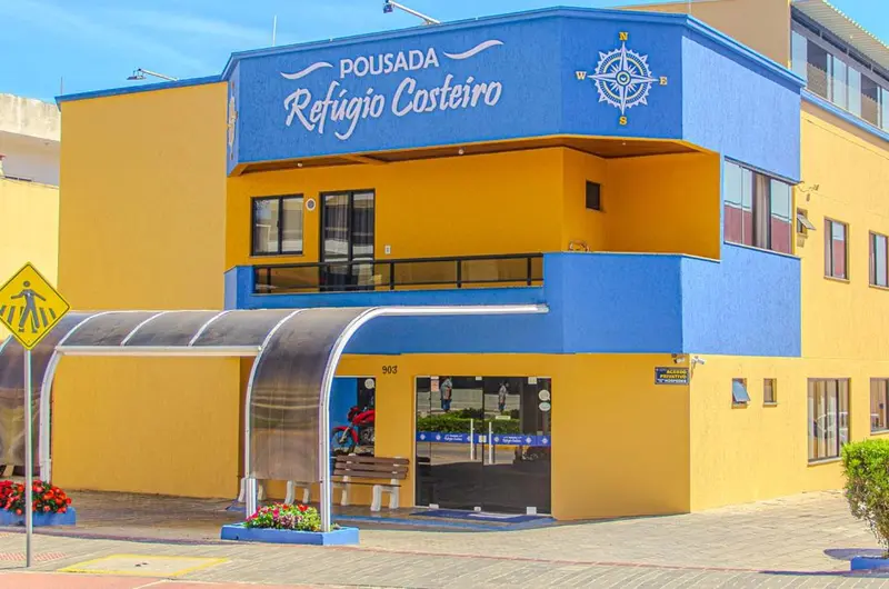 Façade jaune et bleue d'un bâtiment avec un auvent et une signalisation piétonne.