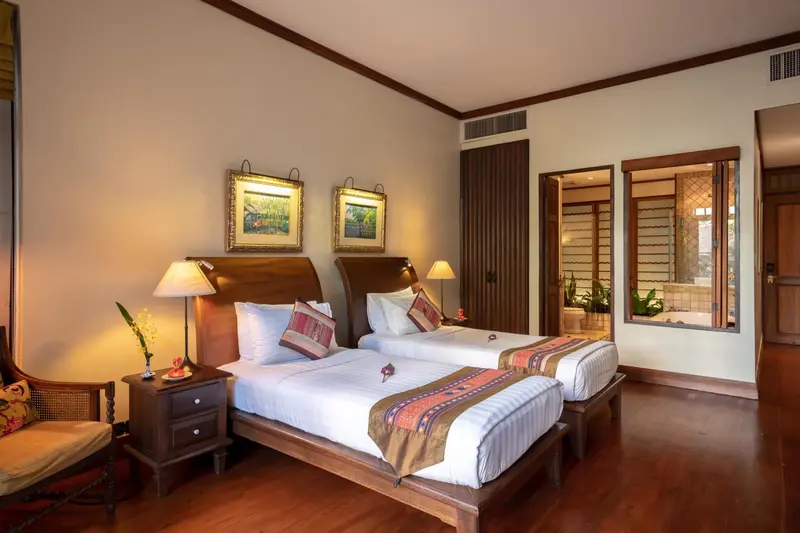 Chambre lumineuse avec deux lits simples et décoration florale.