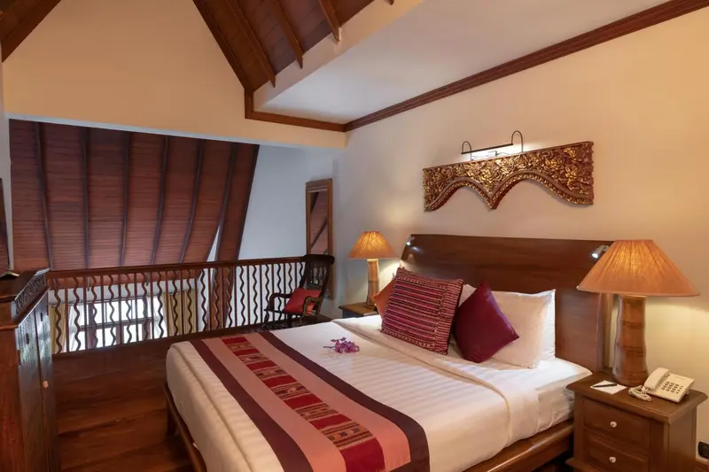 Une chambre avec un grand lit et une décoration en bois sculpté.
