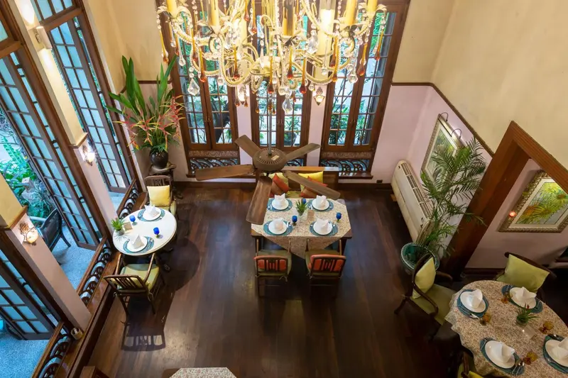 Une salle à manger lumineuse avec des tables dressées et un lustre imposant.