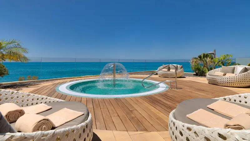 Terrasse avec jacuzzi et chaises longues face à la mer.
