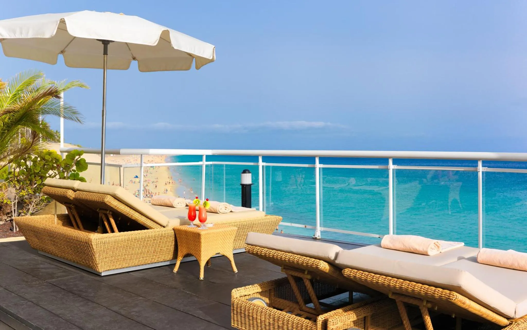 Transats et table basse sur une terrasse en bois avec vue sur la mer.