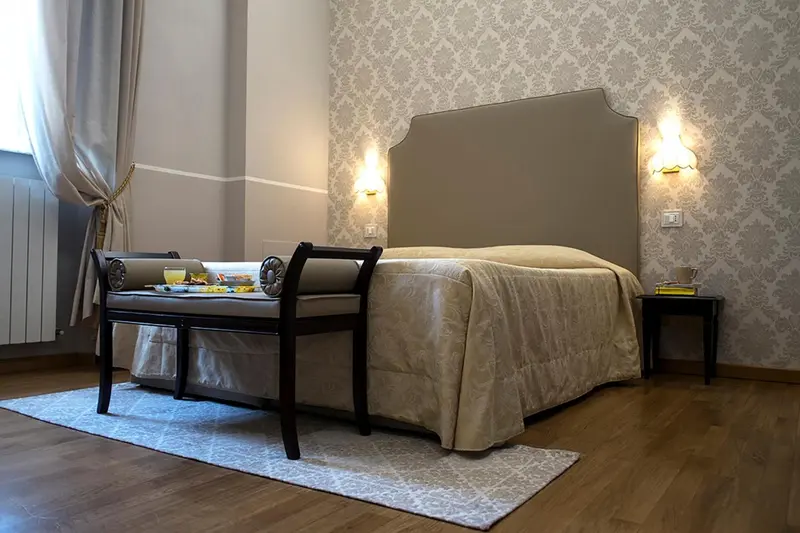 Une chambre à coucher avec un grand lit et un banc au pied du lit.