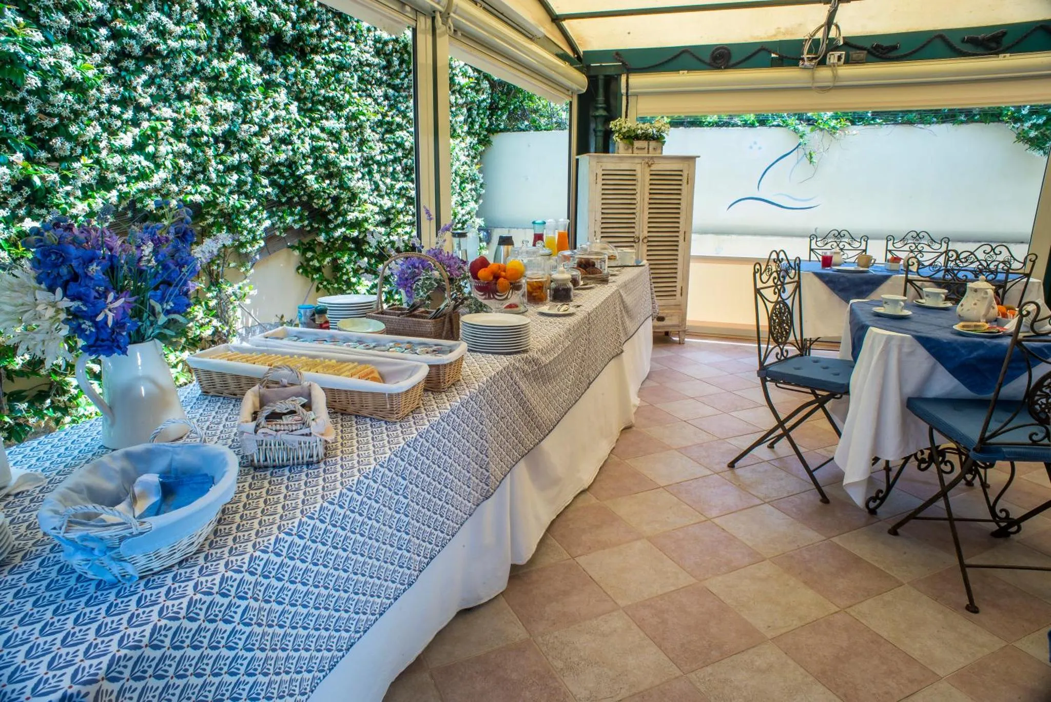 Une table garnie de mets est présentée sur une terrasse ombragée.