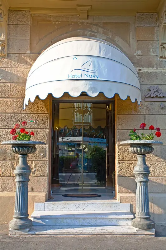Entrée d'un bâtiment avec un auvent rayé et des pots de fleurs.