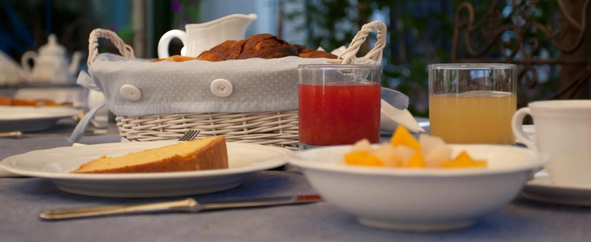 Une table est dressée avec des viennoiseries, des fruits et des boissons.