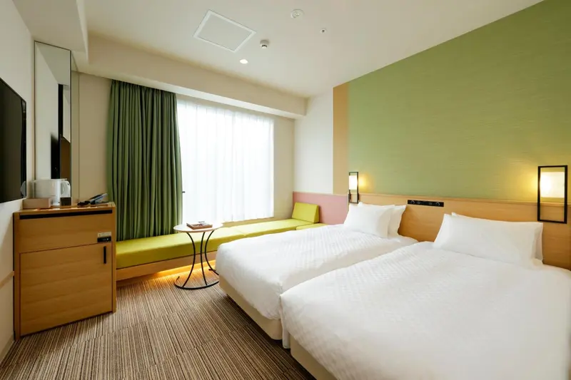 Une chambre lumineuse avec deux lits simples et un coin salon.